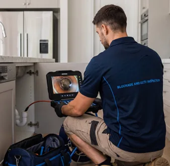 Plumber clearing a blocked toilet in a Killarney Heights bathroom